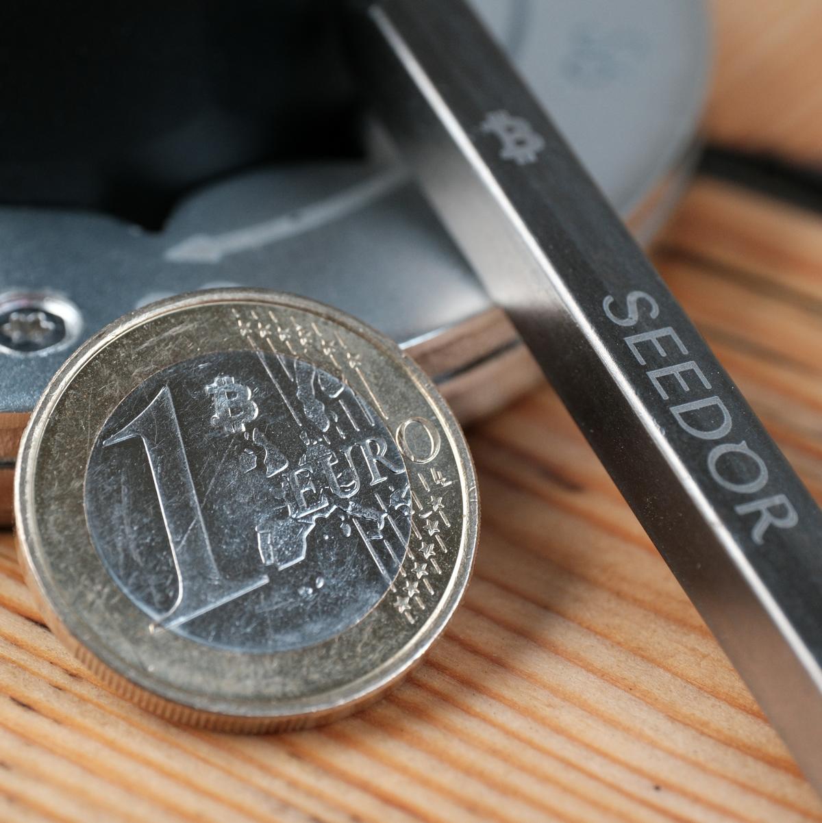 Poinçon Bitcoin Seedor posé à côté d'une pièce de 1 euro marquée ₿